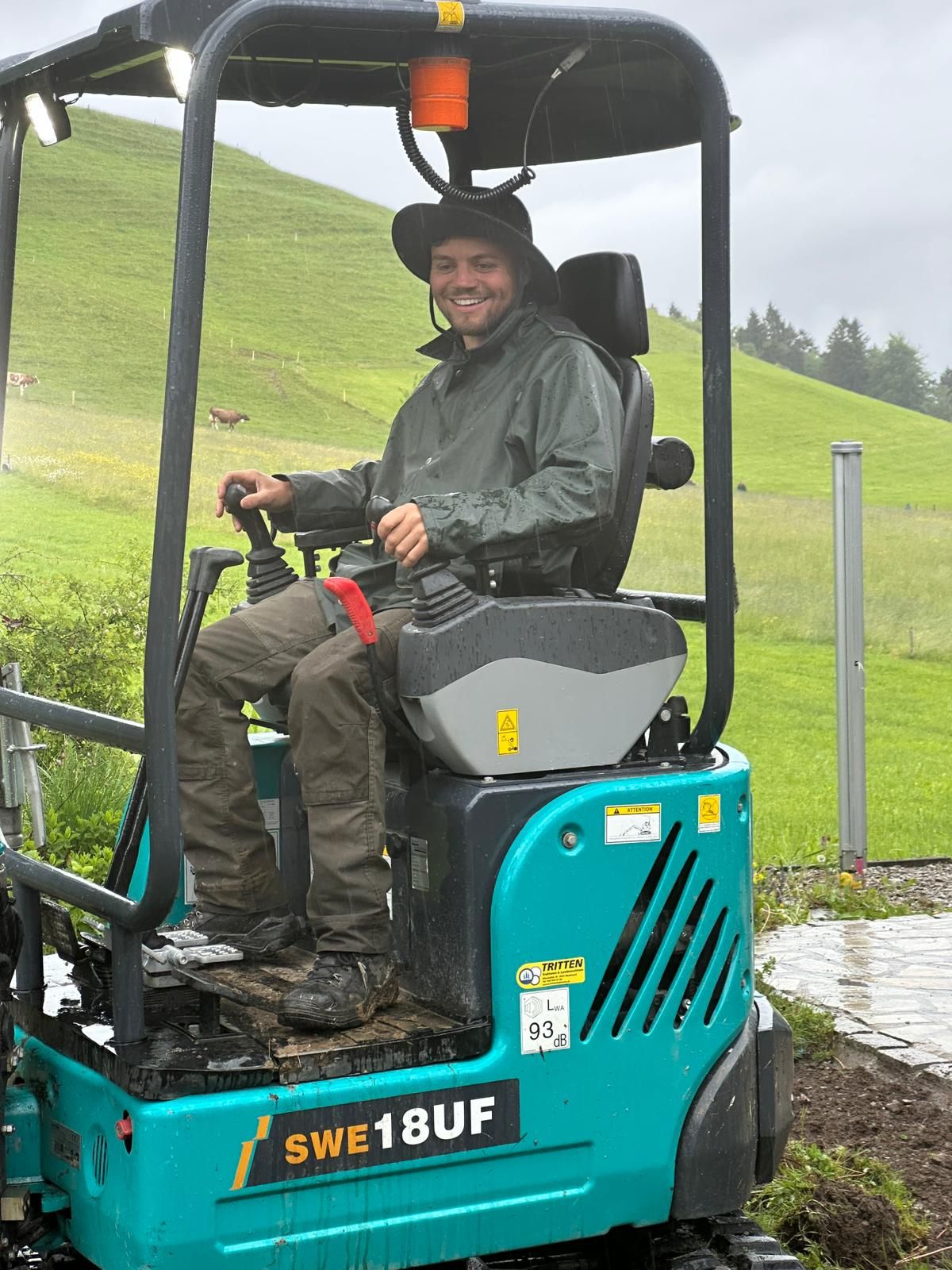 Gärtner auf einem türkisen Kleinbagger